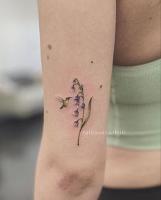 a small flower tattoo on the right arm and leg, with purple flowers growing out of it