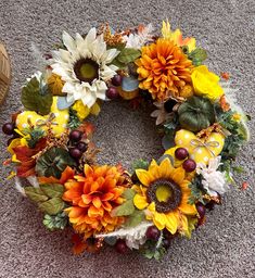 a wreath with sunflowers and other flowers on the ground