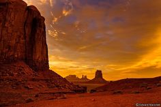 the sun is setting over monument butte in monument national park