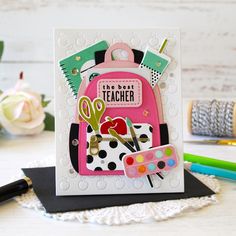 a card with scissors and a pink backpack