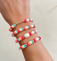 a woman's arm with multi colored bracelets on top of her wrist and an earring in the middle