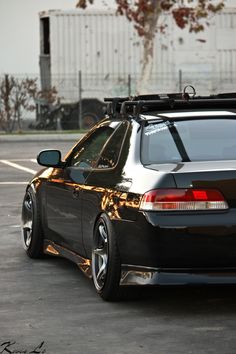 the back end of a black car parked in a parking lot