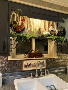 a kitchen sink under a mirror with roosters on the window sill above it