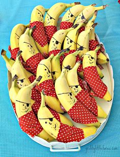 a bunch of bananas with faces on them in a bowl sitting on a blue table cloth