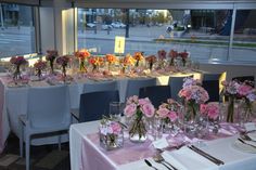 the tables are set up with pink and white flowers in vases, plates and silverware