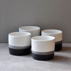 three black and white bowls sitting next to each other on top of a gray surface