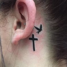 a woman with a cross behind her ear and a bird on the back of her ear