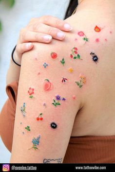 a woman's arm with flowers on it, and the back of her body is covered in tattoos