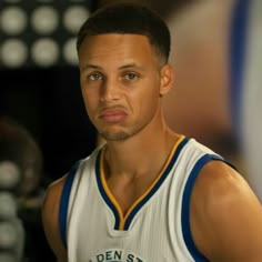 a close up of a basketball player wearing a white and blue uniform looking at the camera