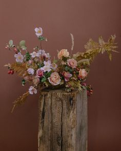 a wooden vase filled with flowers on top of a table next to a brown wall