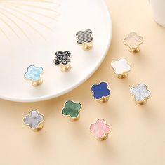 six different colored flower shaped knobs on a white plate next to a coffee cup