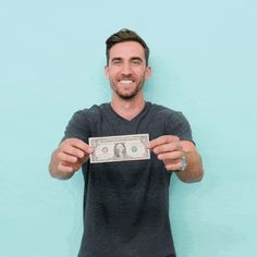 a man holding up a dollar bill in front of his face