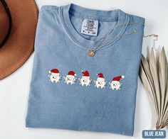 a blue t - shirt with santa's on it next to some feathers and a hat