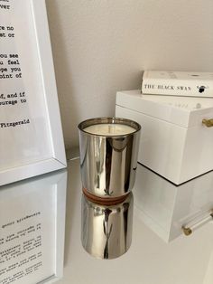 a silver cup sitting on top of a table next to a white box and some books