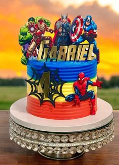 a birthday cake with the name captain america on it and superheros in the background