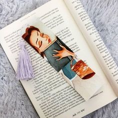 an open book with a drawing of a woman's face on it and a tassel