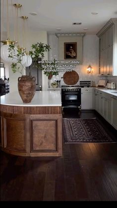 a large kitchen with an island in the middle and wood flooring on the other side