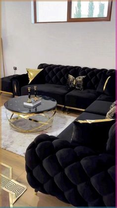 a living room with black velvet couches and gold accents on the coffee table in front of it