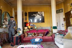 a man standing in the middle of a living room filled with couches and chairs