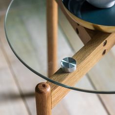 a glass table with a wooden base and metal knobs on the top, in front of a tiled floor