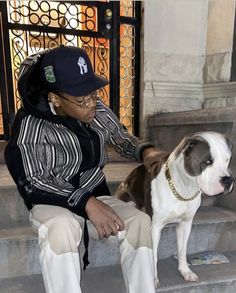 a woman sitting on the steps petting a brown and white pitbull dog