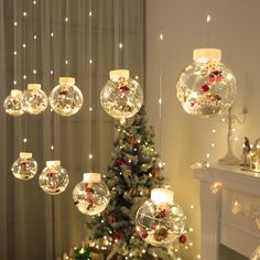 christmas decorations hanging from the ceiling in front of a fire place with a lit tree