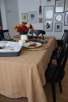 a dining room table with plates and flowers on it's placemats in front of pictures