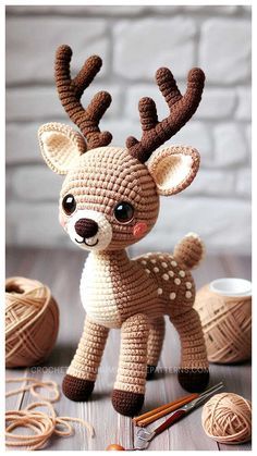 a crocheted deer is standing next to some yarn balls and needles on the table