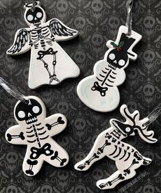 four decorated christmas ornaments with skulls and bones in the shape of angels on a black background