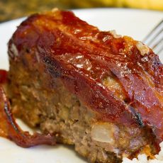 a piece of meat sitting on top of rice next to a fork