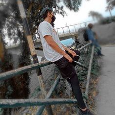 a man riding a skateboard on top of a metal hand rail next to trees