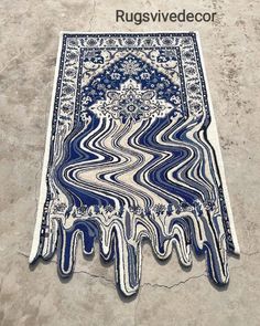 an artistic rug is on the ground with blue and white paint drips coming out of it