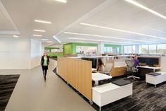 an office with two people walking through the room and several cubicles on each side