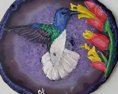 a painting of a hummingbird with tulips on it's back side