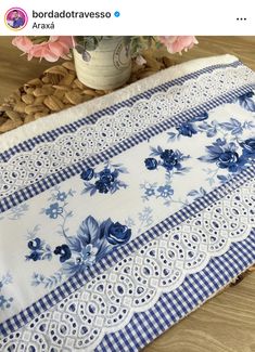 blue and white table cloth with flowers on it, next to a potted plant