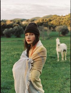 a woman standing in a field next to a white horse