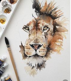 a watercolor painting of a lion's head with paintbrushes next to it