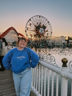 a woman standing on a pier next to a ferris wheel