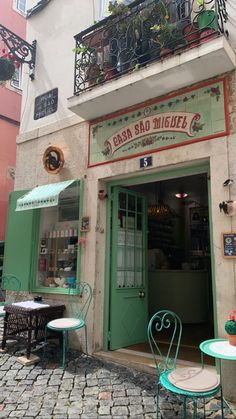 an outdoor cafe with tables and chairs in front of the door, on a cobblestone street