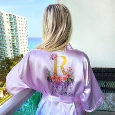 Experience the luxury of our kimono floral robe with a unique monogram design. This silk robe for women is not just a custom bathrobe, it's a statement of elegance and sophistication. Perfect as a bridal robe for the bride, it adds a touch of glamour to your special day. Our women's bathrobe is made from the finest satin, ensuring a comfortable fit and a luxurious feel. The bride robe is adorned with a beautiful floral pattern, making it a stunning floral robe. Personalize your robe with our per Spring Wedding Sleepwear With Kimono Sleeves, Pink Satin Finish Robe For Wedding, Wedding Robe With Kimono Sleeves For Spring, Spring Wedding Robe With Kimono Sleeves, Feminine Satin Robe For Summer, Feminine Satin Summer Robe, Feminine Summer Satin Robe, Summer Wedding Satin Robe, Spring Wedding Satin Sleepwear