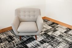 a chair sitting on top of a black and white rug in front of a wall