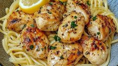 some chicken and noodles with lemon wedges on the side