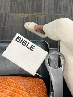 a woman sitting on top of a chair next to a pair of scissors and a bible