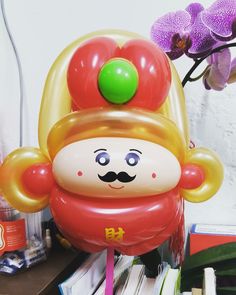 an inflatable balloon with a clown's face on it sitting next to a purple orchid