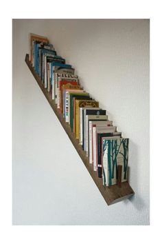 the books are lined up on the wall to go down the stair case that is made out of wood