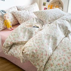 a bed covered in pink and white floral sheets