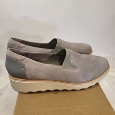 Elevate Your Shoe Game With These Stylish And Comfortable Clarks Sharon Dolly Slip-On Loafers. Made With High-Quality Suede Fabric, These Shoes Feature A Round Toe Shape And Elastic Accents For A Snug Fit. Available In A Solid Gray Color, They Are Perfect For Casual Or Workwear Occasions. The Low Wedge Heel And Cushioned Insole Provide All-Day Comfort, Making Them Ideal For Walking. These Shoes Are A Must-Have For Any Fashion-Forward Woman Who Wants To Look Good Without Sacrificing Comfort. Get Slip-on Platform Loafers With Removable Insole And Closed Toe, Slip-on Suede Platform Loafers For Spring, Spring Suede Slip-on Platform Loafers, Suede Loafers With Medium Width And Round Toe, Medium Width Suede Loafers With Round Toe, Spring Low-top Medium Width Loafers, Spring Medium Width Low-top Loafers, Leopard Print Loafers, Low Heel Wedges