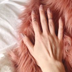 a woman's hand with two small tattoos on her fingers