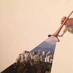 a man holding a trumpet in front of a cityscape with mountains behind him