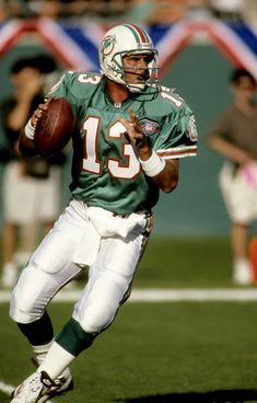 a football player running with the ball in his hand and people watching from the sidelines